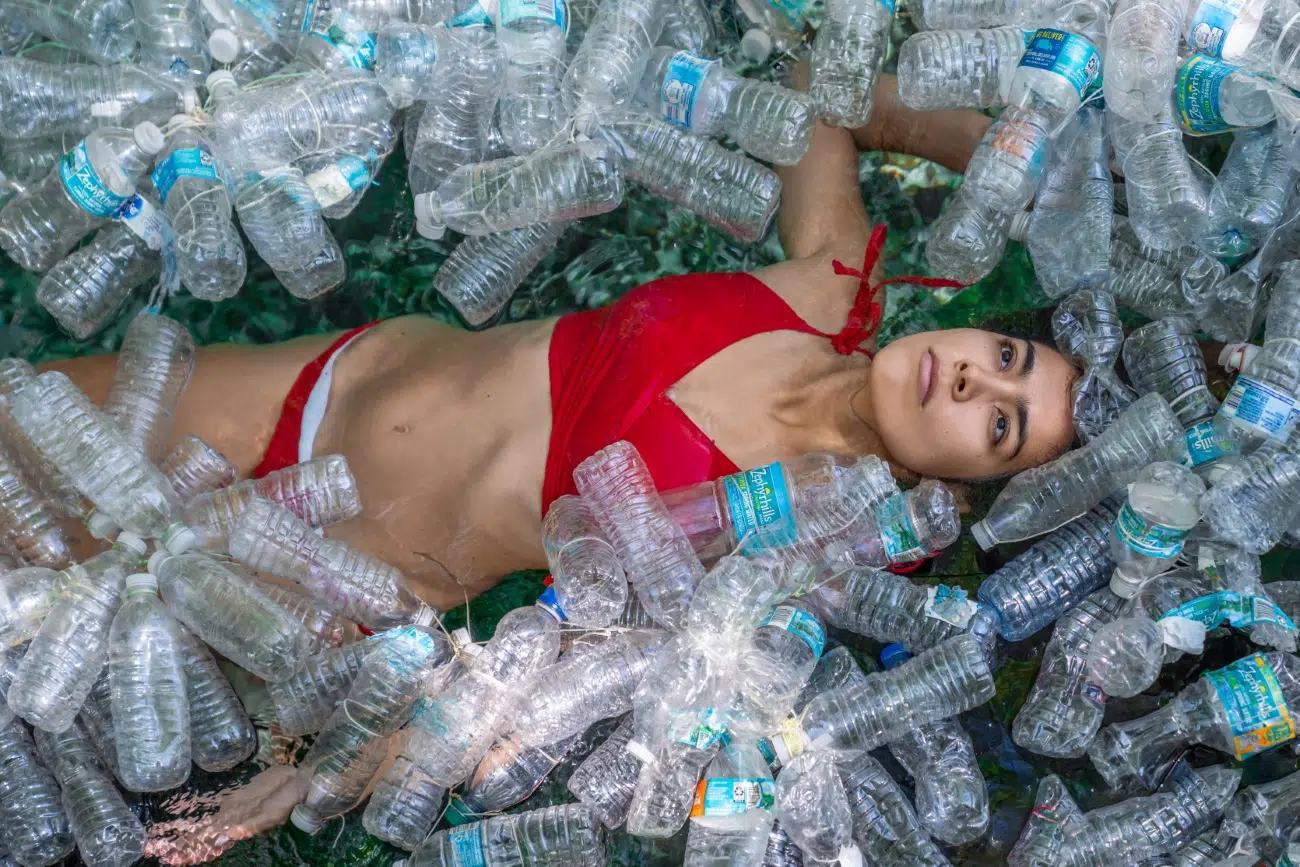 Woman in a bikini immersed in plastic bottles