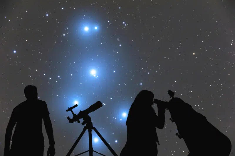 Three people looking at a starry sky